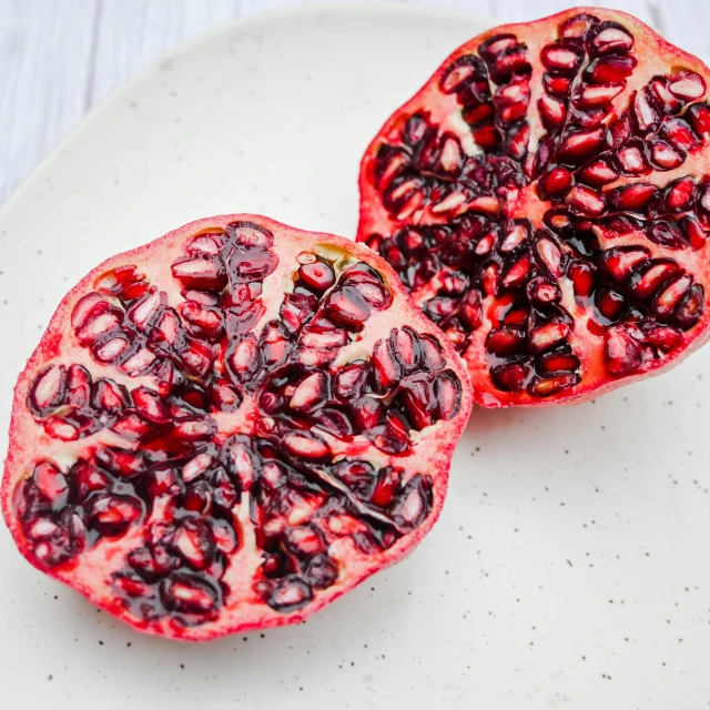 two halves of pomegranate on a white plate