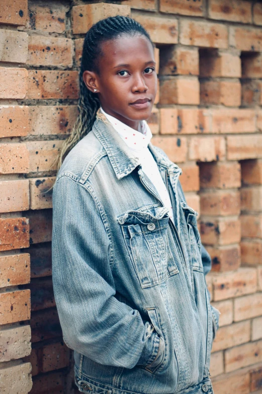 a girl standing near a brick wall with her hair in a id