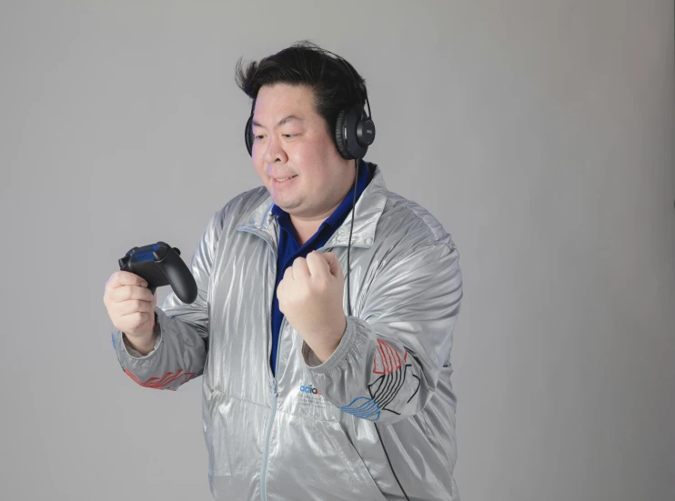 an oriental man in earphones is holding a controller