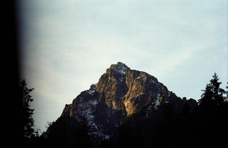 a mountain peak with trees behind it in silhouette