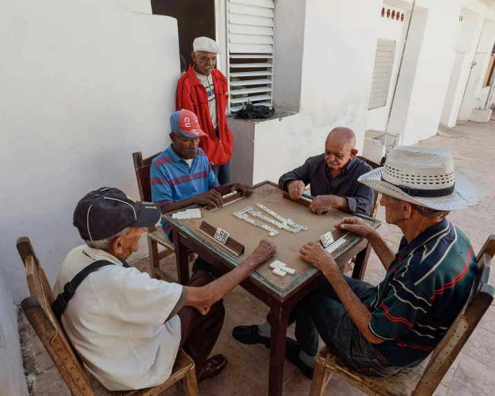 four men sitting at a table playing a game