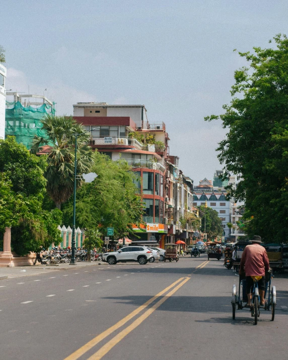 man on bicycle riding down a street lined with parked cars