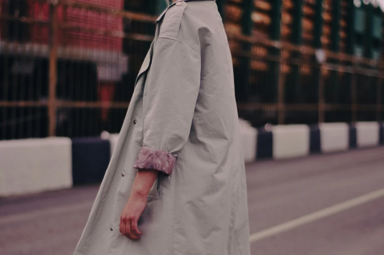 a woman in a trench coat walking down a street