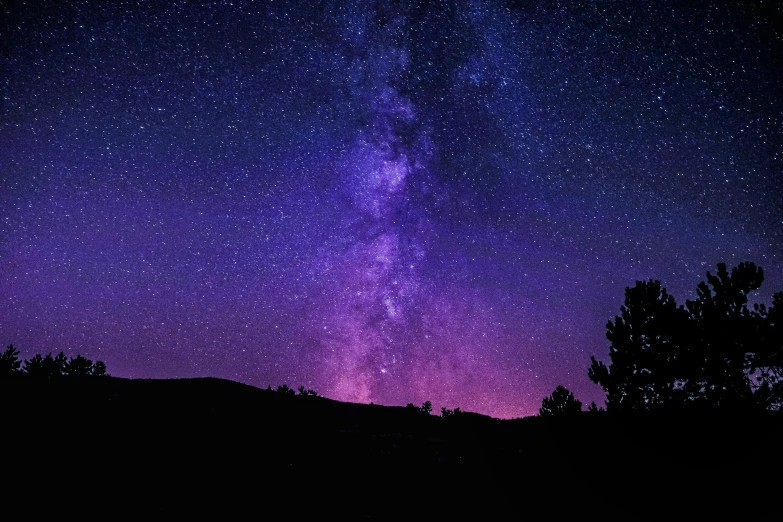 the night sky and the stars above a hill