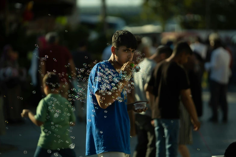 a boy in a blue shirt blowing bubbles