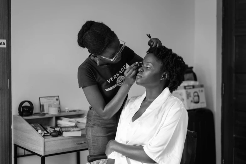 a woman standing up while  another woman's hair