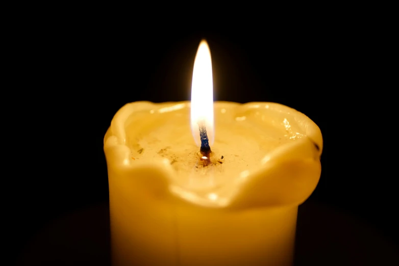 a single yellow candle is shining in the dark