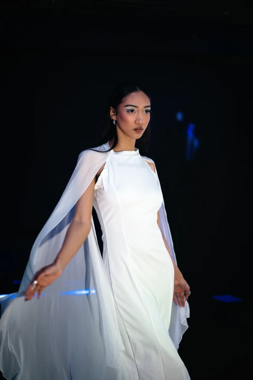 a woman in white is walking down the runway