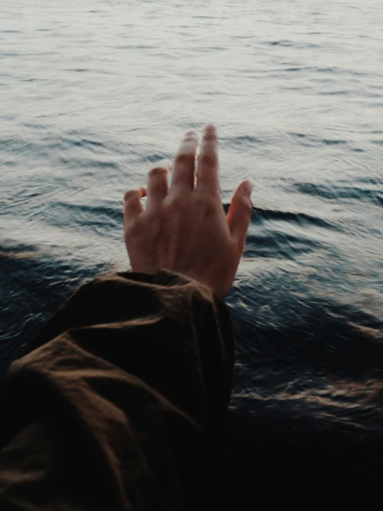 the hand is holding soing in front of the water