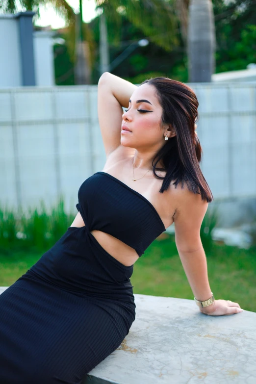 a beautiful young woman leaning on top of a cement block