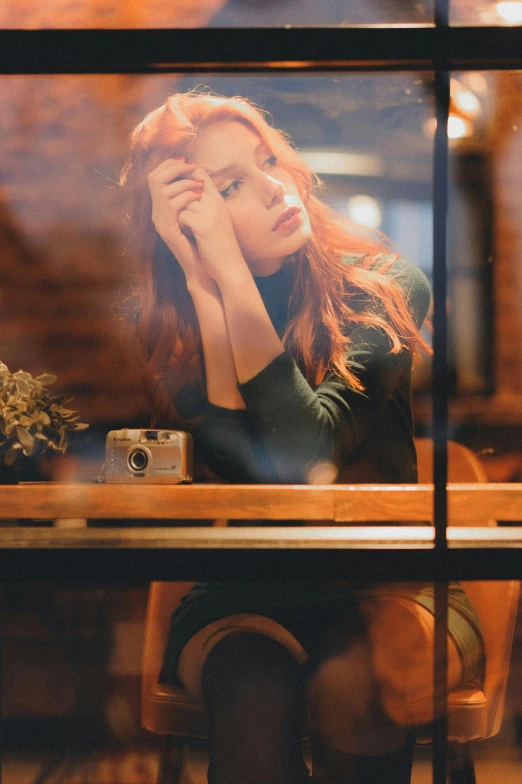 a woman sits on her phone and holds her hand to her face