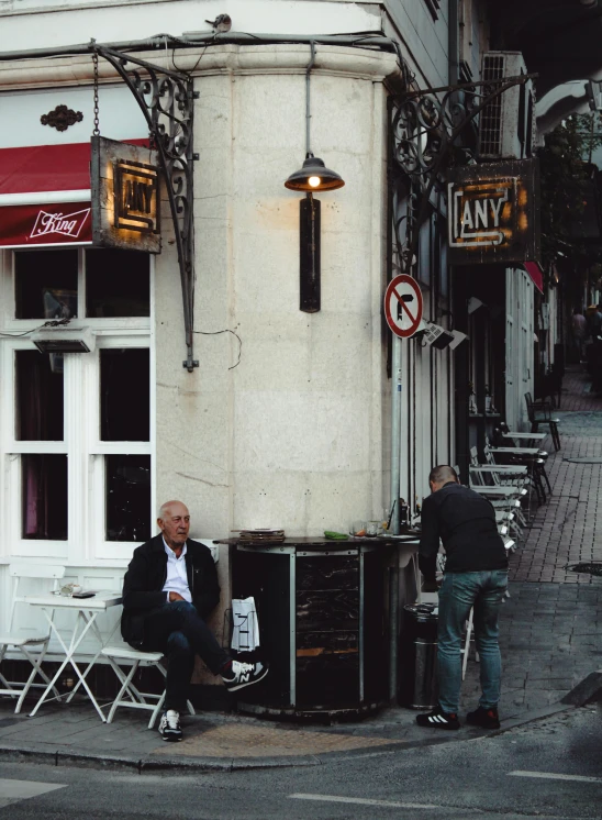 an old man sitting on the side of the street