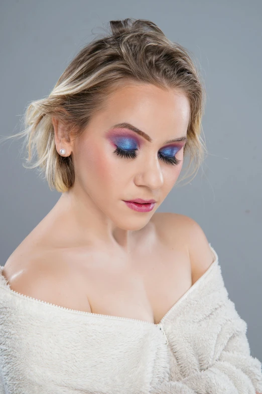 a woman with blue makeup looks down at the camera