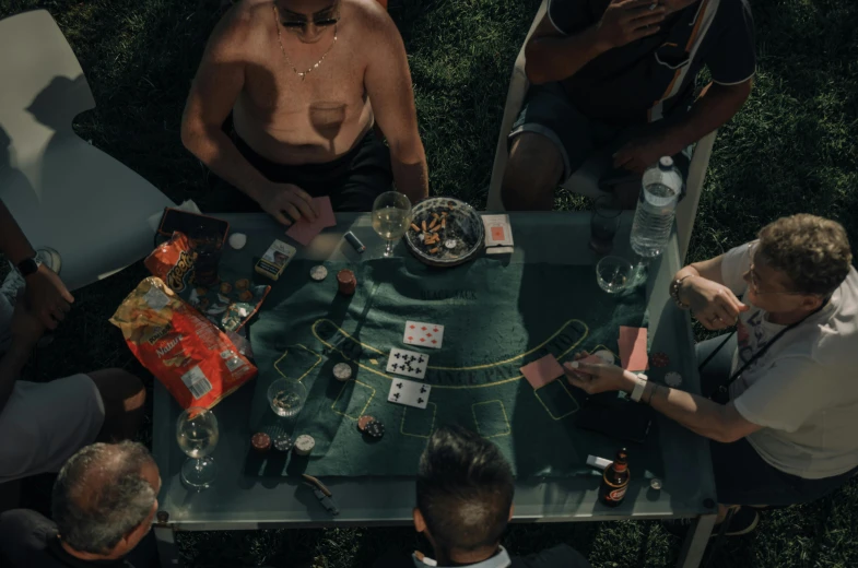 four people are sitting at a table playing cards