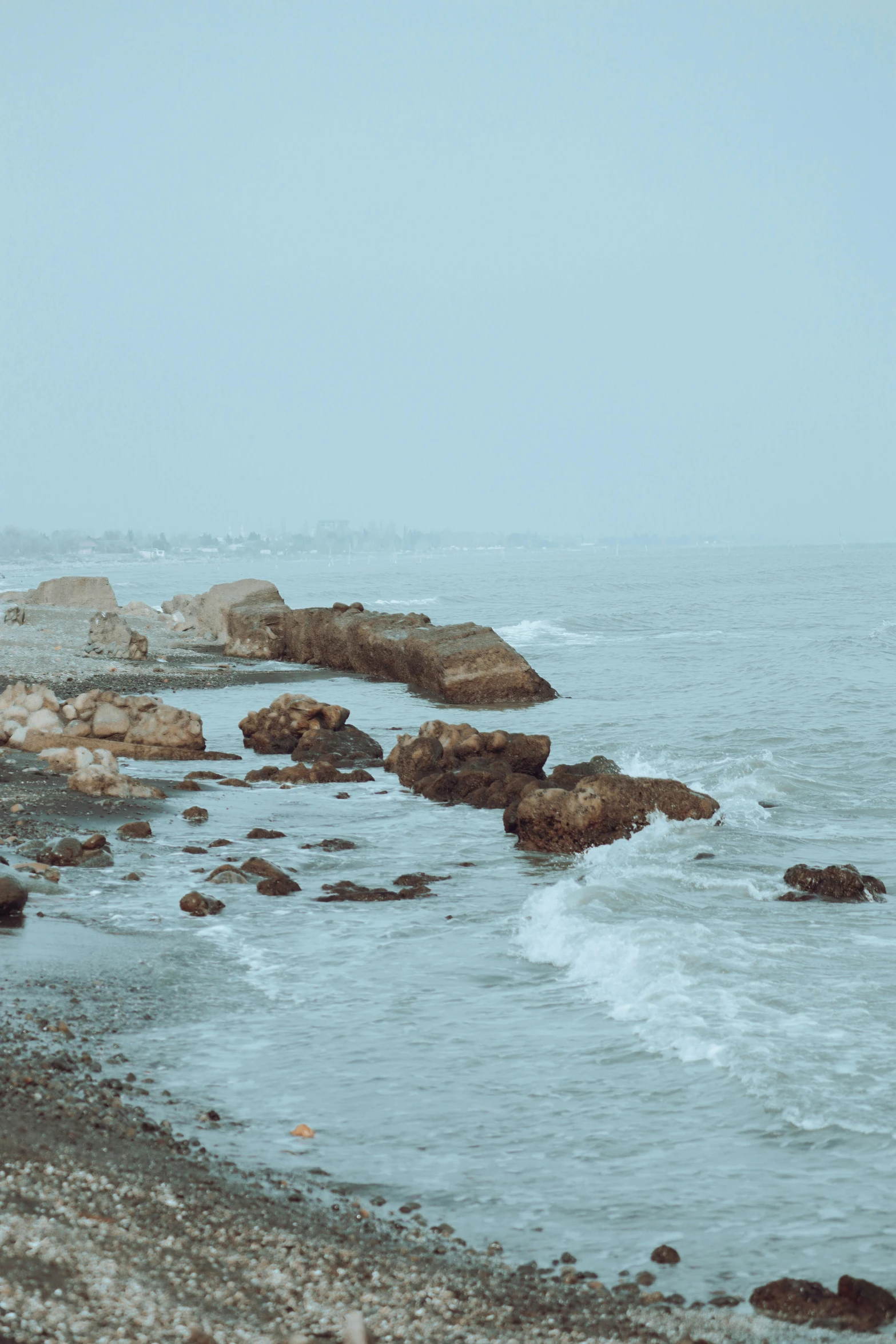 a person stands near the rocks on the shore