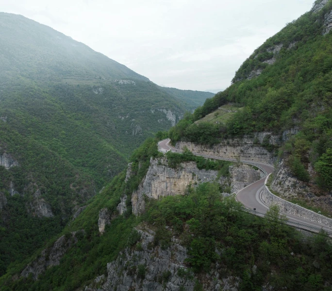 an over head view of a narrow road between a mountainside and a body of water