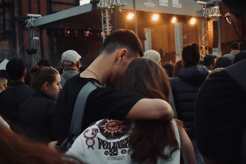 a guy standing hugging someone near the crowd of people