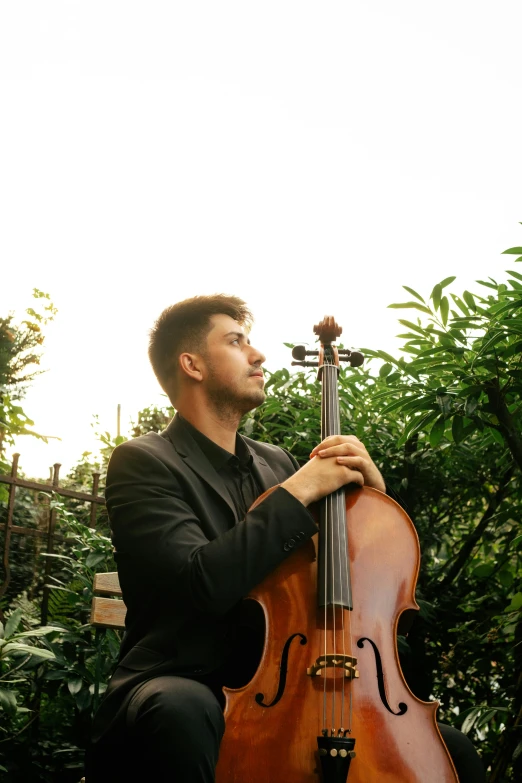 a man is sitting down and playing a cello