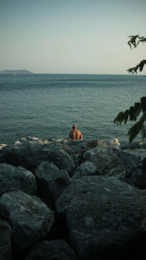 a man and child sitting on rocks near water