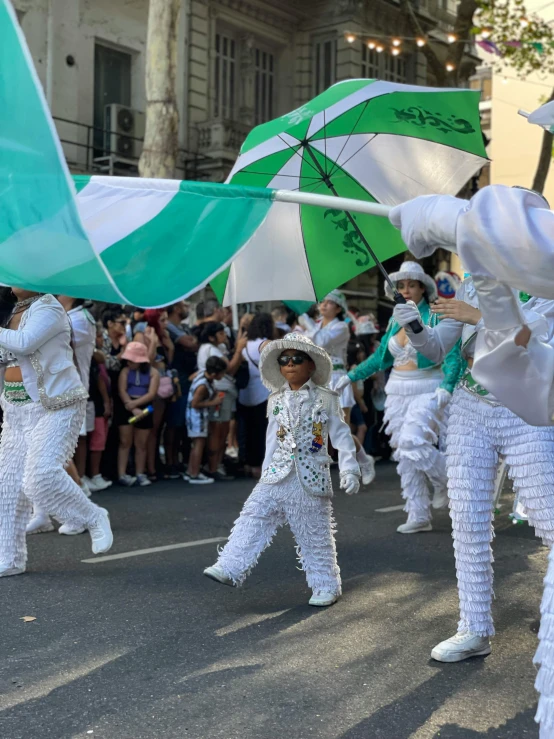 several people in white costume with umbrellas marching in the street