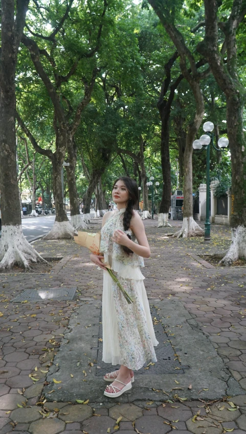 a girl stands in a park holding onto soing