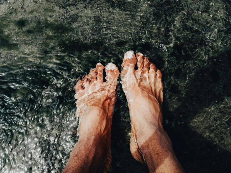 someone standing in shallow water with their feet in the water