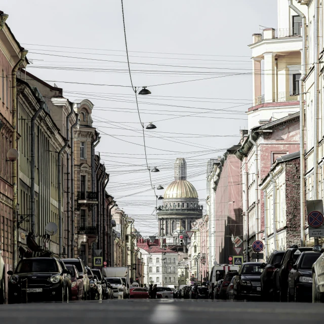 the sky is gray, with cars driving along it and power lines are above buildings