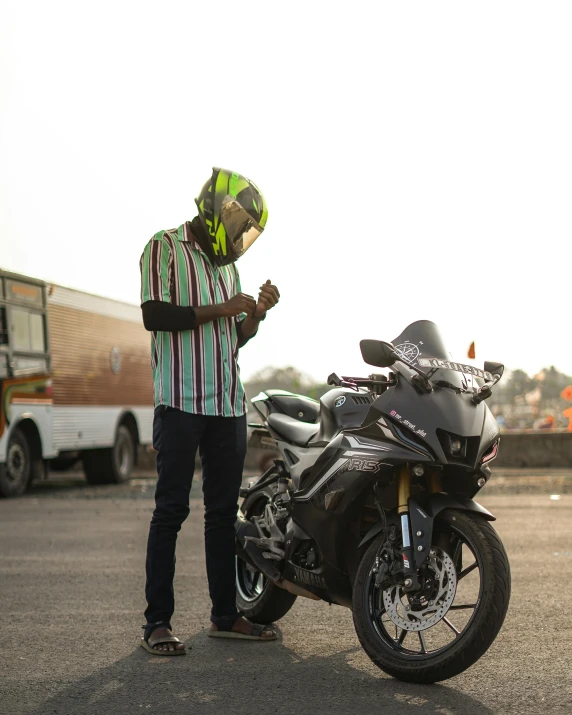 man on the street next to motorcycle with his helmet open