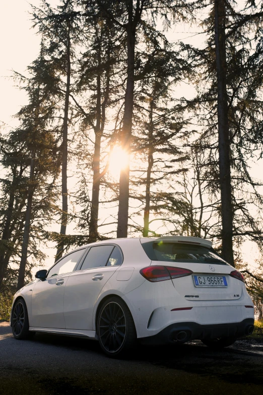 a white car parked on the side of the road with trees in the background