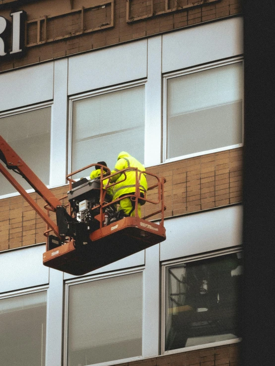 two construction workers are working on the side of a building