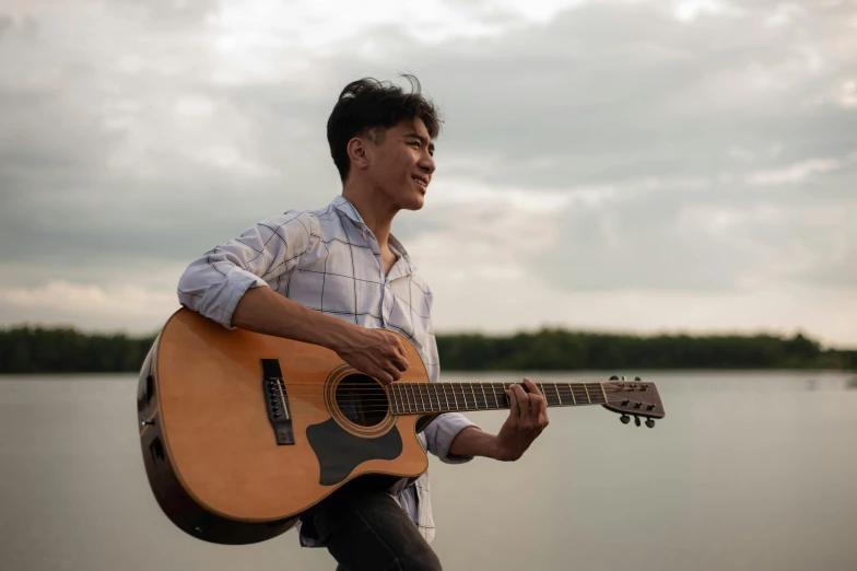 a man with an acoustic guitar at the beach