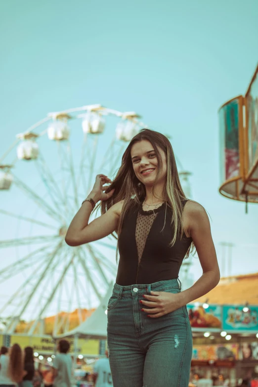 a woman in high waist jeans posing in front of a ferris wheel