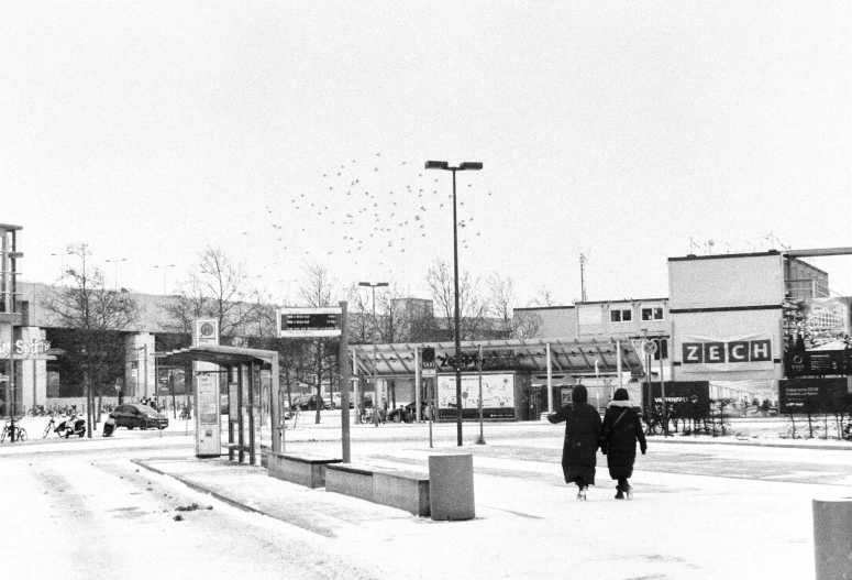 black and white image of a man standing at the bus stop