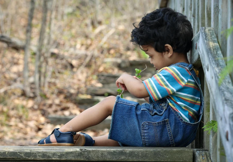 a little boy sitting on top of a wooden bench