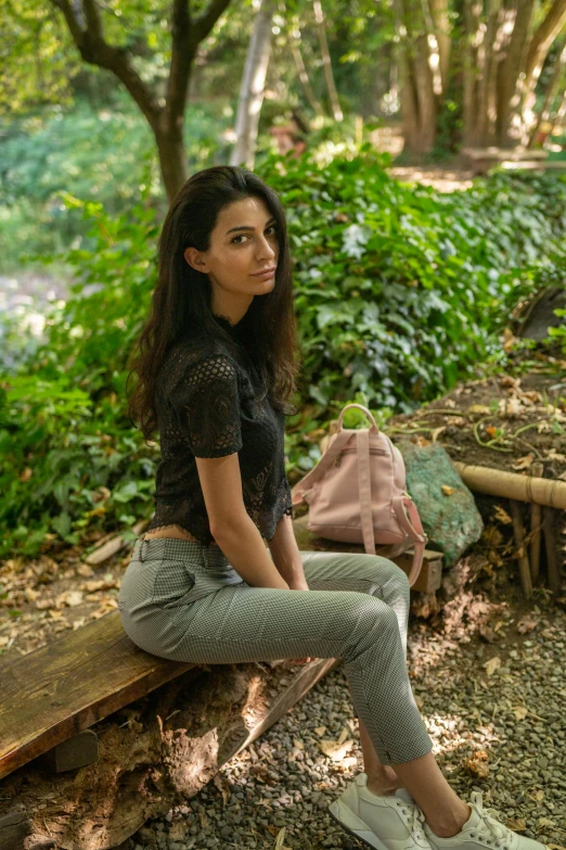 a woman sits on the side of a log in front of a stream