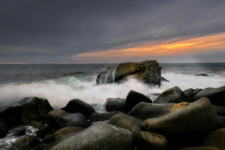 large rocks covered in white foam under a gray sky