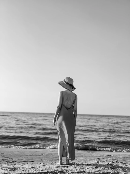 a woman wearing a hat looking out to sea