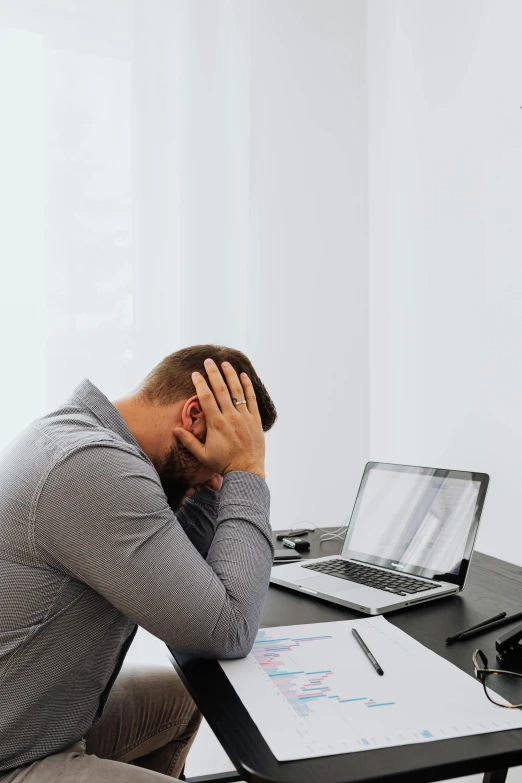 man at desk with hand resting head in hand