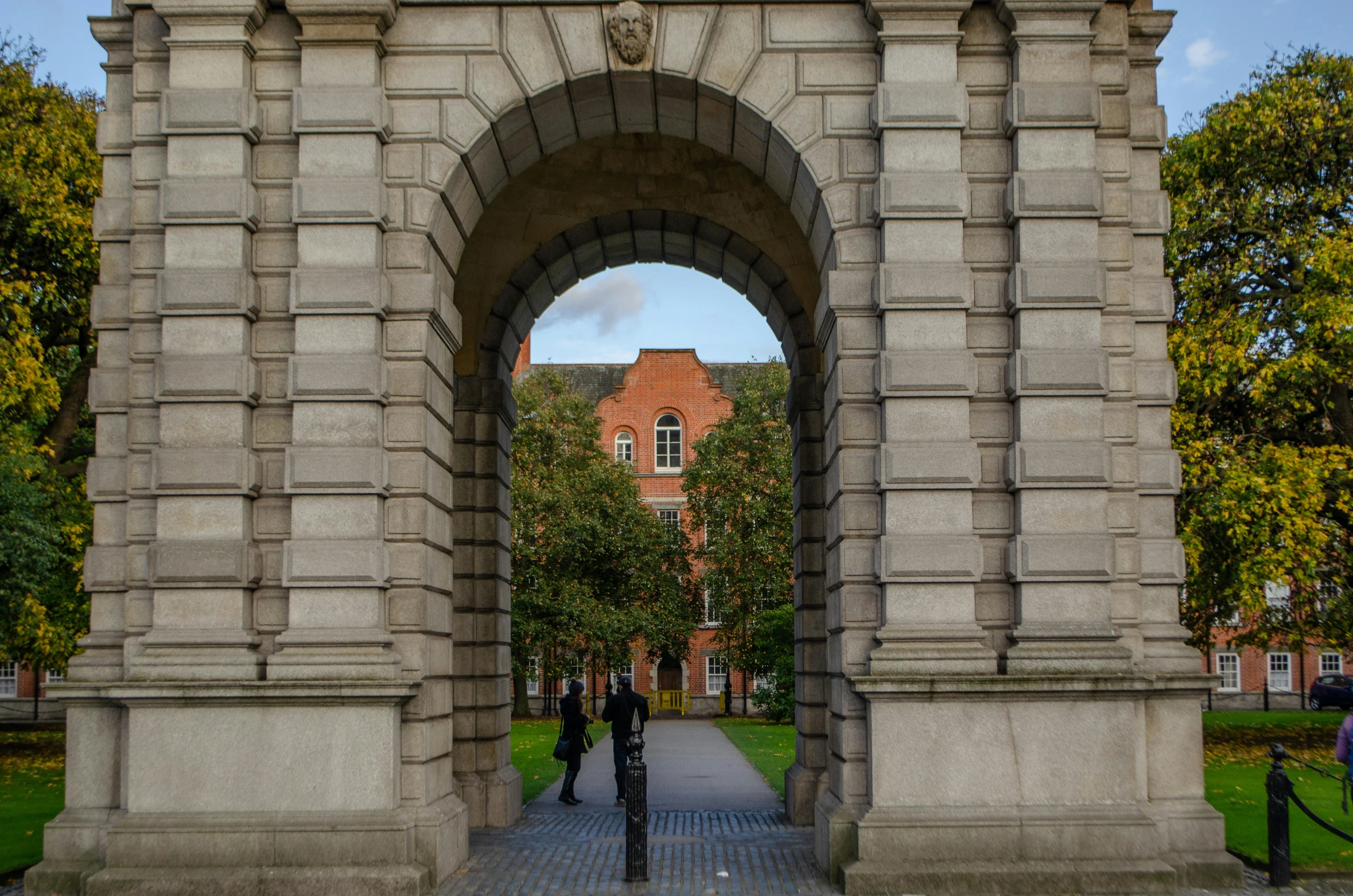 two people are standing in front of an arch with a clock on it