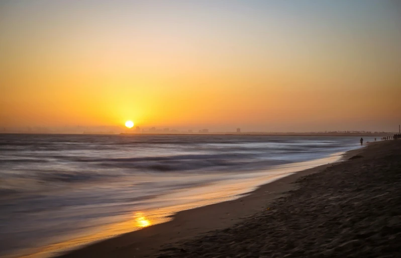 there is a person that is standing on the beach at sunset