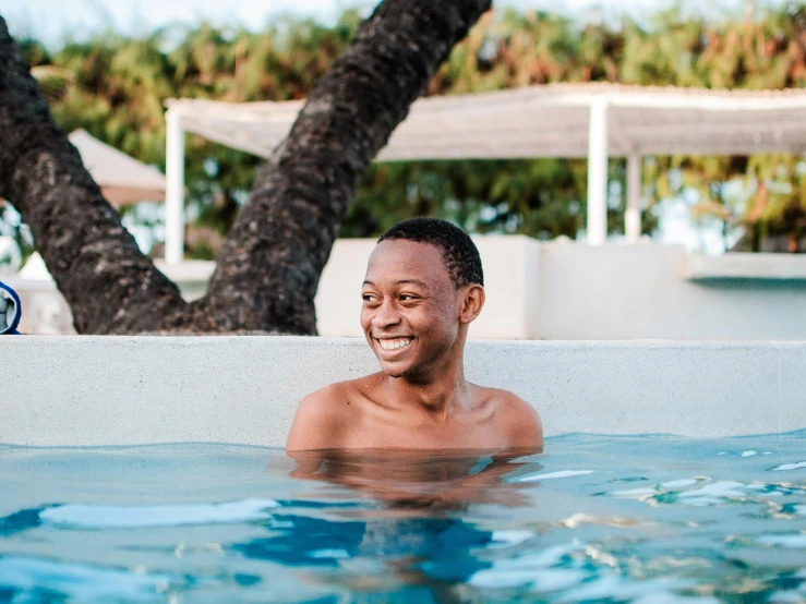 a man sitting in a pool smiling with  on