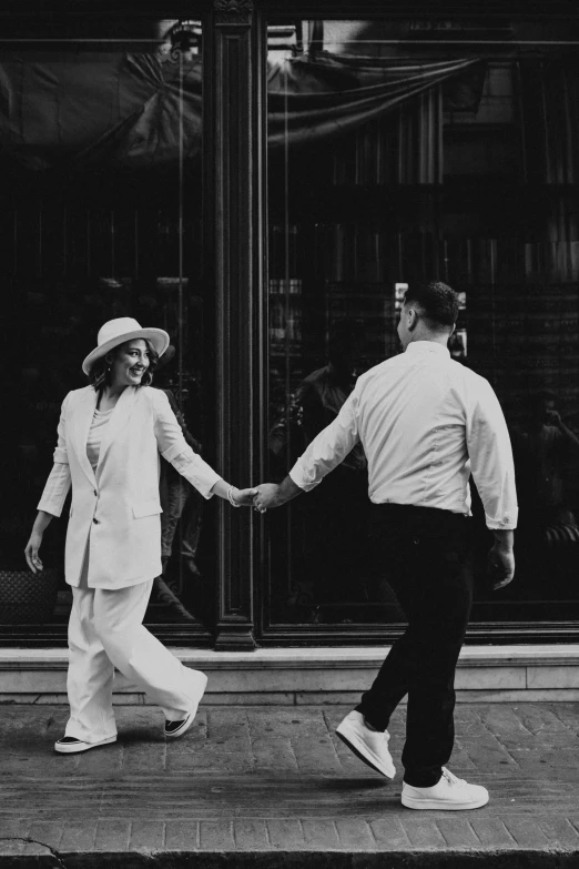 a man and woman walk down the street holding hands