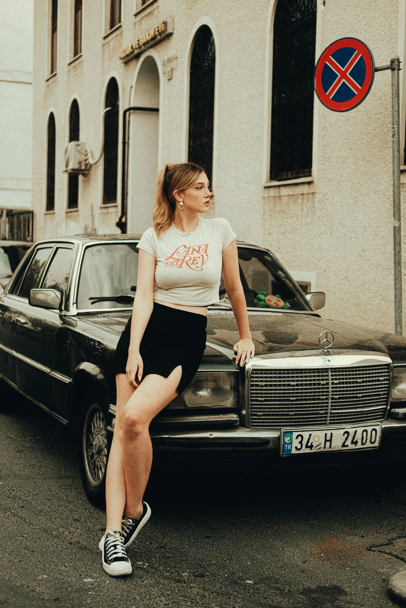 a beautiful woman leaning against a black car