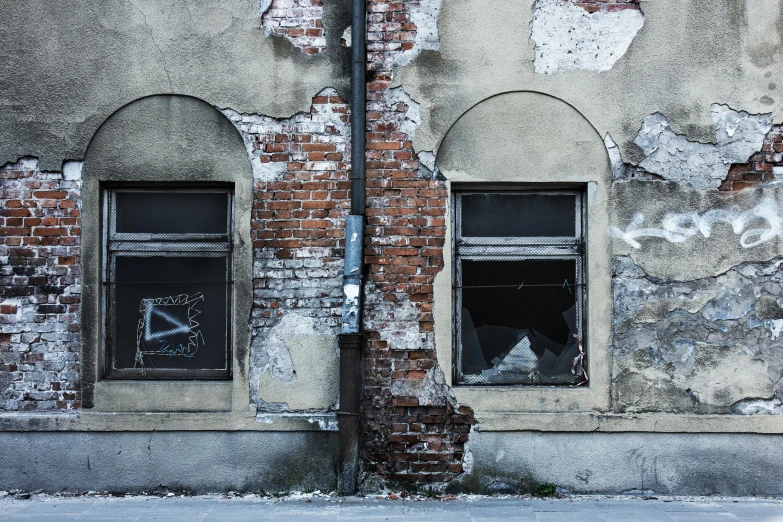 two windows that are attached to an old wall