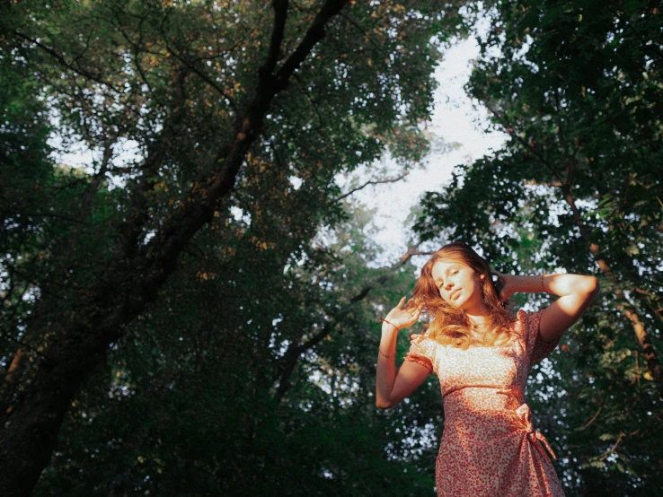 the girl is standing beneath tall trees posing for a picture