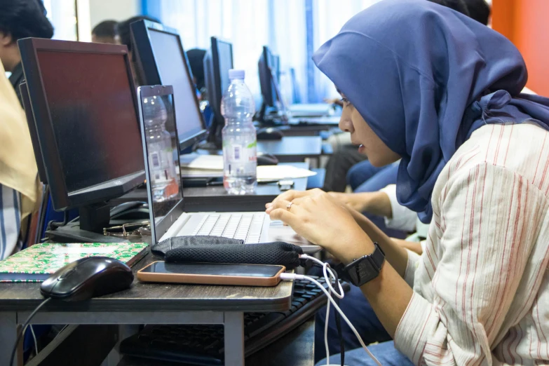 a woman sitting at a desk in front of two laptops