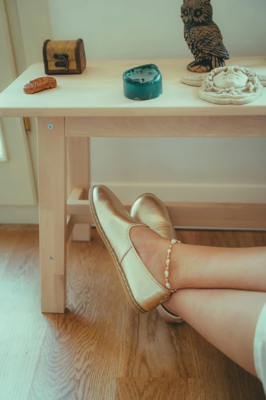 a person wearing a pearled gold sling sandal sitting on a small table