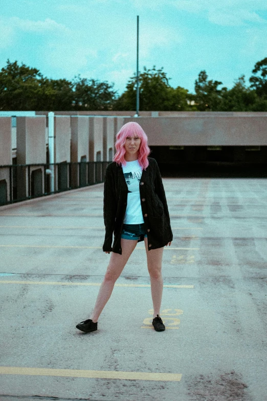 a woman with pink hair standing on a road