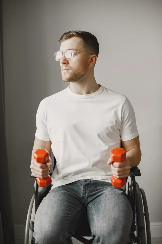 a man in a wheelchair holds two orange dumbs