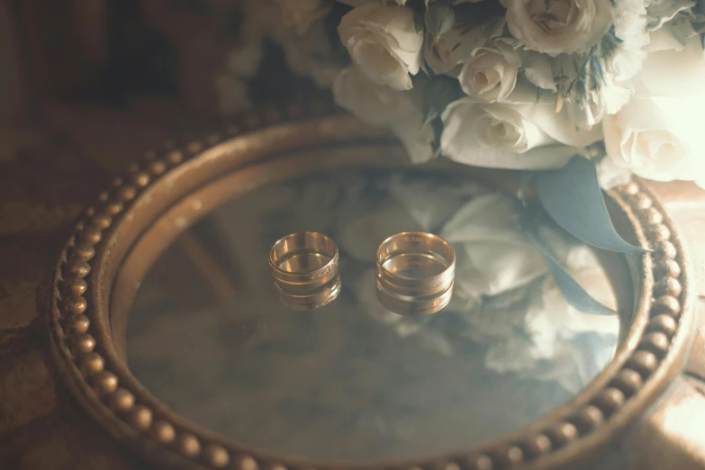 gold wedding bands resting on a tray with flowers